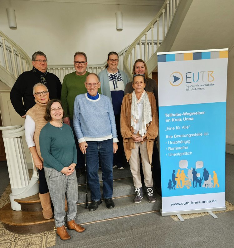 Auf dem Bild ist das Team der EUTB im Kreis Unna zu sehen. Die Personen stehen auf einer Treppe. Neben ihnen ist ein Roll-Up. Die Namen stehen unter dem Bild.