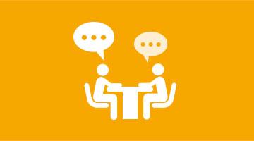 Icon zeigt zwei Personen im Dialog am Tisch