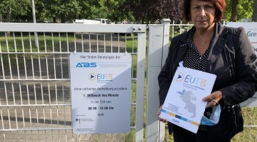 Die Mitarbeiterin, Frau Klewer, steht am Tag der Eröffnung eines Beratungsangebots in einer Außenstelle. Sie hält in ihren Händen Materialien des EUTB-Angebotes und lächelt.