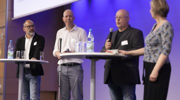 Menschen an Stehtischen auf Bühne