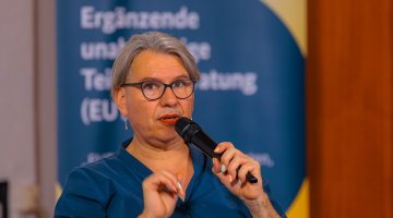 Referierende Person sitzt auf der Bühne